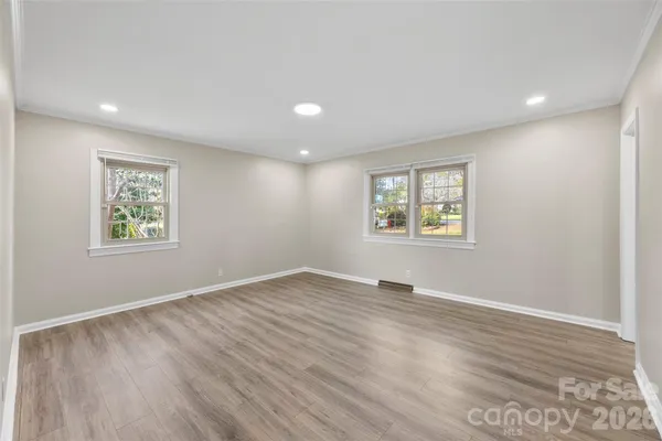 a view of an empty room with a window and wooden floor