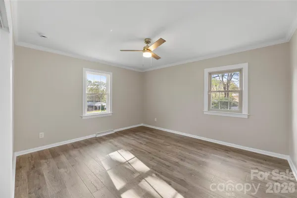 a view of empty room with wooden floor and fan