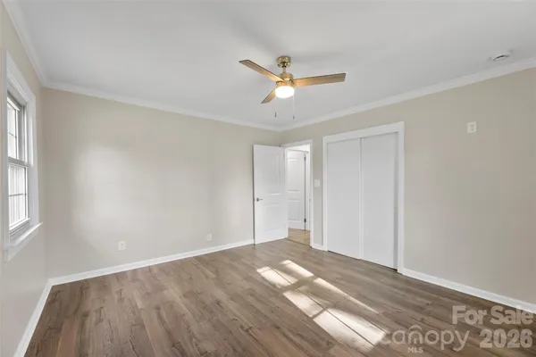 a view of empty room with wooden floor and fan