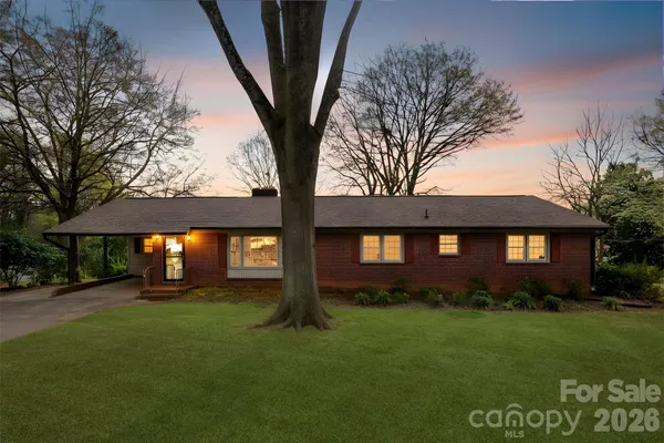 a brick house next to a yard with a large tree