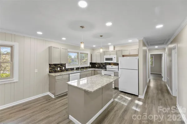 a kitchen with stainless steel appliances kitchen island a refrigerator sink and white cabinets