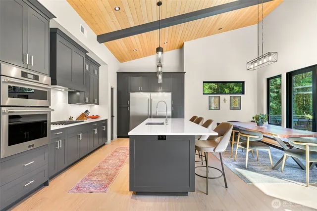 a large kitchen with a large counter top space a sink stainless steel appliances and cabinets