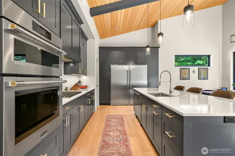 a kitchen with stainless steel appliances granite countertop a kitchen island a stove a sink and a refrigerator