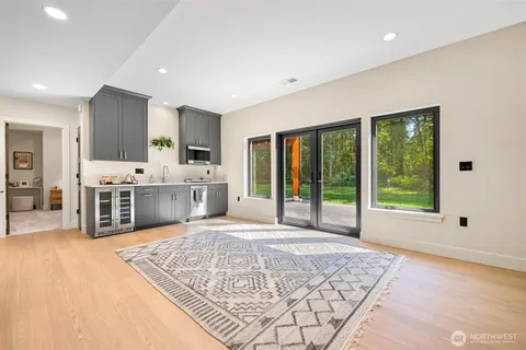 a large white kitchen with kitchen island granite countertop a large window cabinets and stainless steel appliances