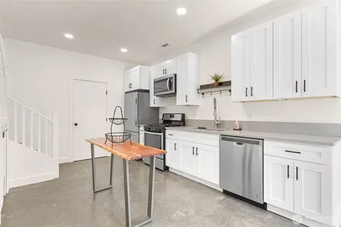 a kitchen with stainless steel appliances granite countertop a white cabinets and a stove top oven