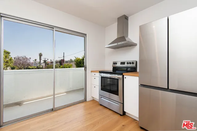 a kitchen with stainless steel appliances a refrigerator a stove and a sink with wooden floor