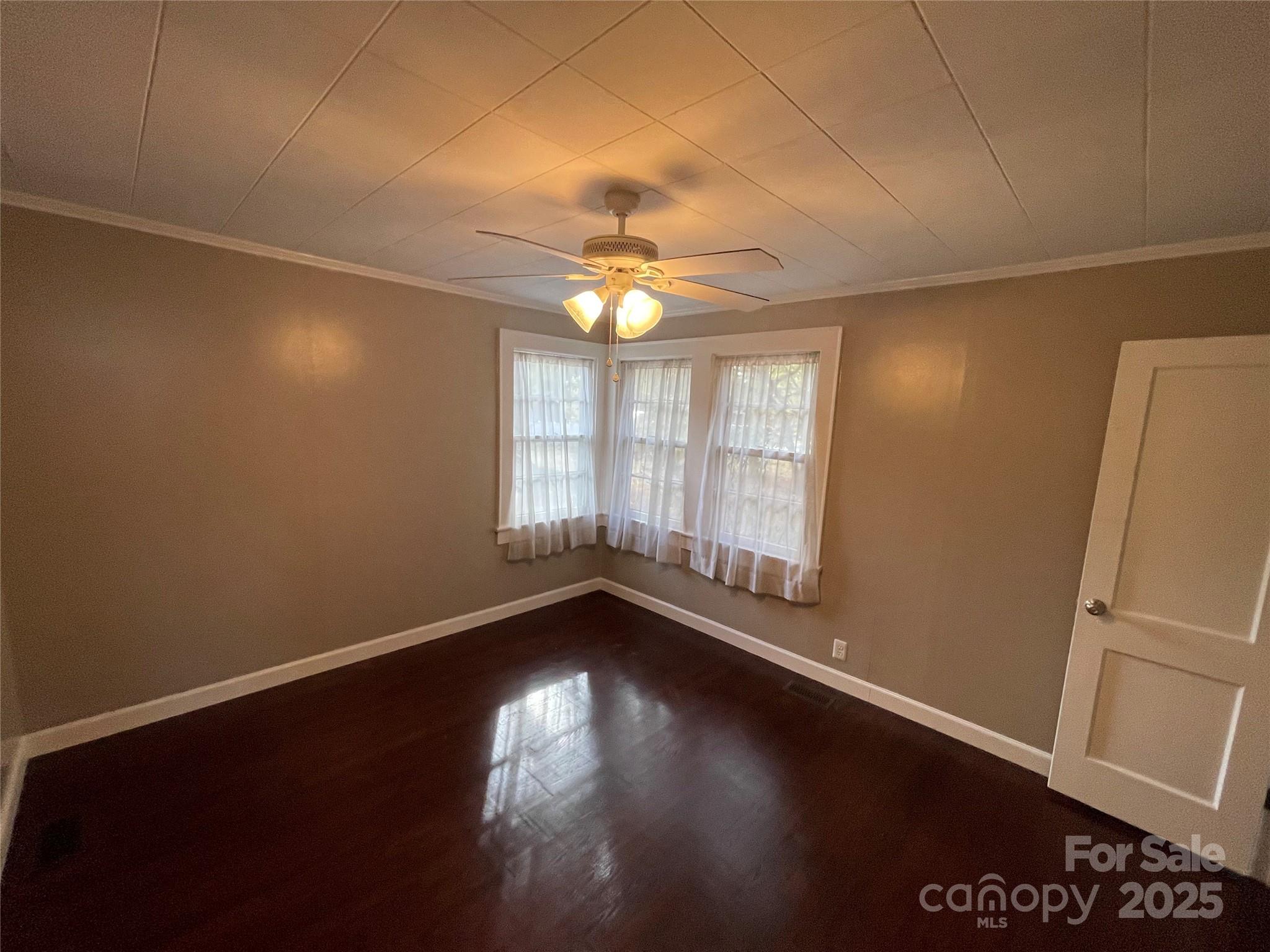 2711 Mooresville Road Salisbury, NC 28147 - Photo 8 of 18 an empty room with wooden floor and windows with curtains