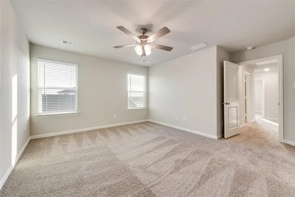 a view of an empty room with window and chandelier fan
