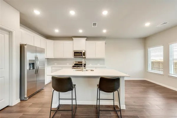 a kitchen with stainless steel appliances kitchen island granite countertop a kitchen island and chairs in it
