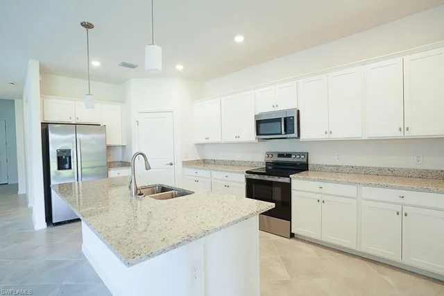 a kitchen with granite countertop a sink a counter top space stainless steel appliances and cabinets
