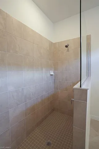 a spacious bathroom with a granite countertop sink two mirror and shower