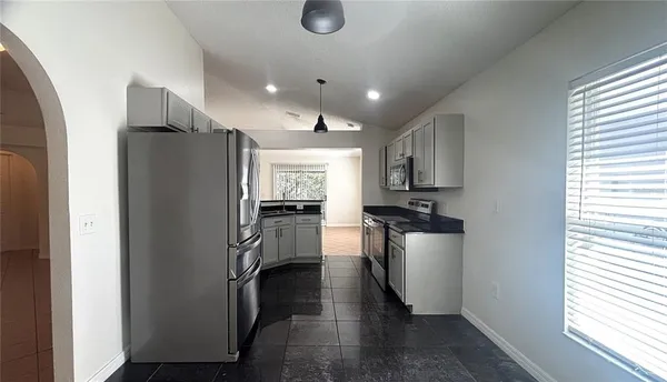 a kitchen with stainless steel appliances granite countertop a refrigerator a stove and a sink