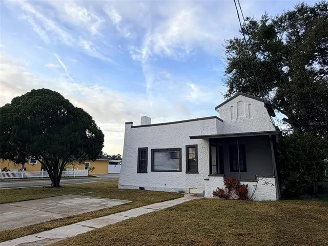 a front view of a house with garden and trees