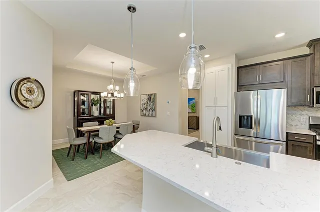 a large white kitchen with a refrigerator a sink dishwasher a oven and a dining table with wooden floor