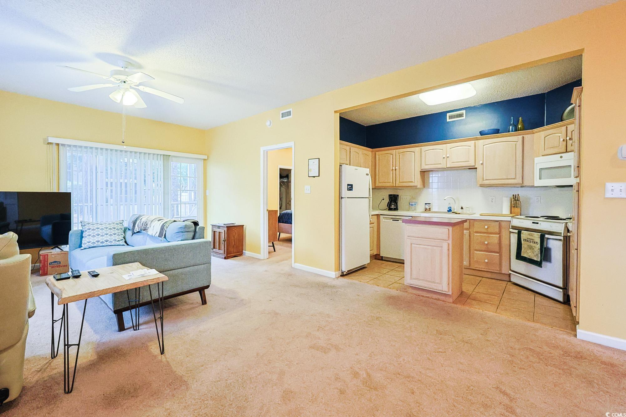 2302 Sweetwater Boulevard, Unit 2302 Murrells Inlet, SC 29576 - Photo 24 of 24 Kitchen with light brown cabinets, white appliances, light colored carpet, light countertops, and open floor plan