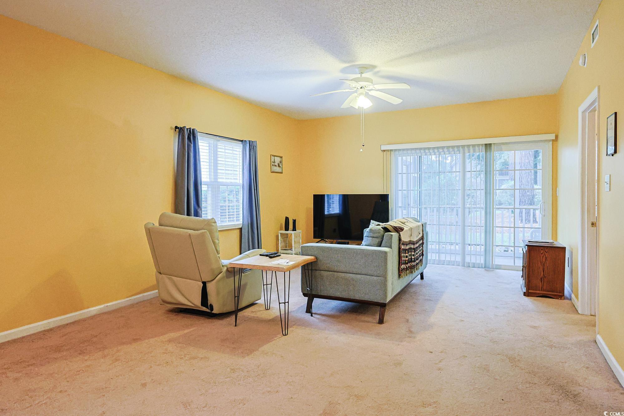 2302 Sweetwater Boulevard, Unit 2302 Murrells Inlet, SC 29576 - Photo 8 of 24 Living area with a textured ceiling, light carpet, and ceiling fan