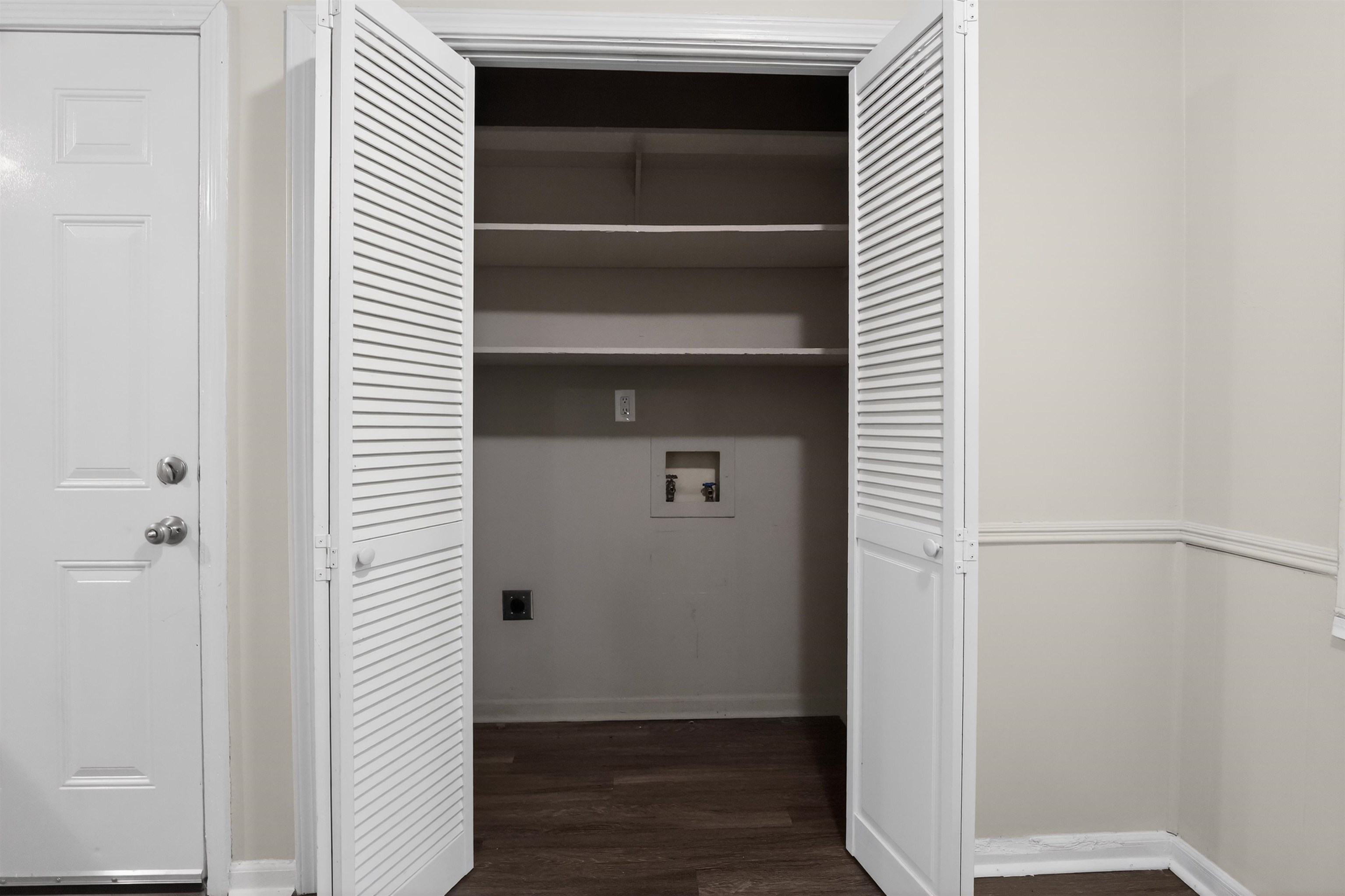 3152 Mackham Avenue Memphis, TN 38118 - Photo 16 of 16 Louvered bifold doors opening to a utility area with shelving, hookups, and wood-finish flooring