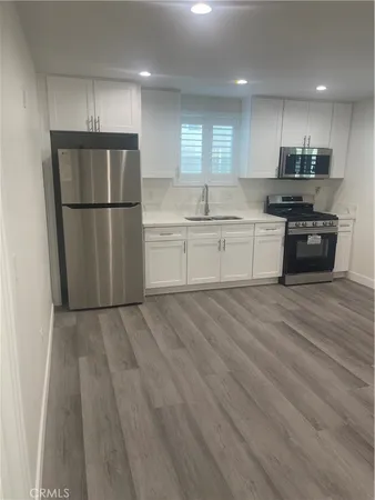a kitchen with granite countertop a refrigerator and a stove top oven