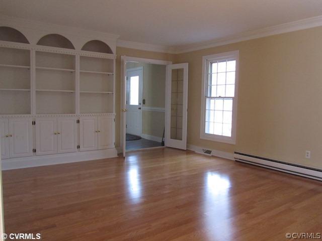 10819 Cherokee Road Midlothian, VA 23113 - Photo 5 of 24 an empty room with wooden floor and cabinet