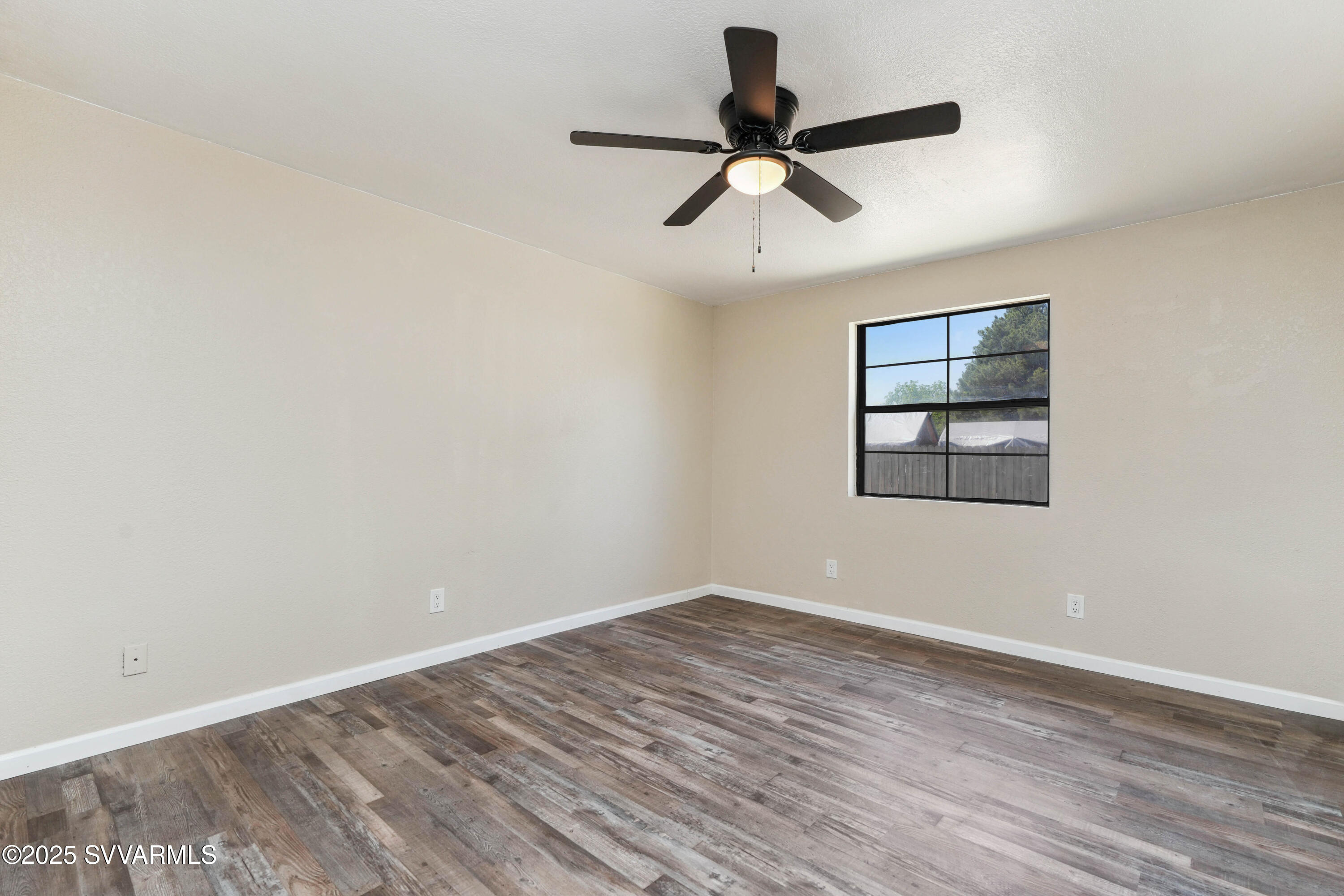 248 South River Cave Road Camp Verde, AZ 86322 - Photo 18 of 36 an empty room with wooden floor ceiling fan and windows