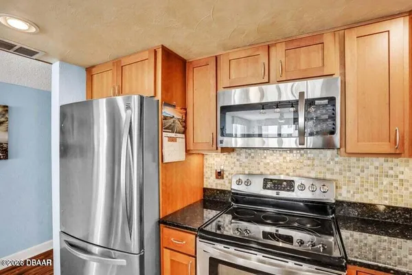 a kitchen with stainless steel appliances granite countertop a refrigerator and a stove top oven
