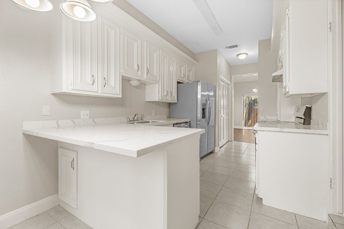 304 East Adoue Street Alvin, TX 77511 - Photo 3 of 12 a kitchen with a sink a refrigerator and cabinets