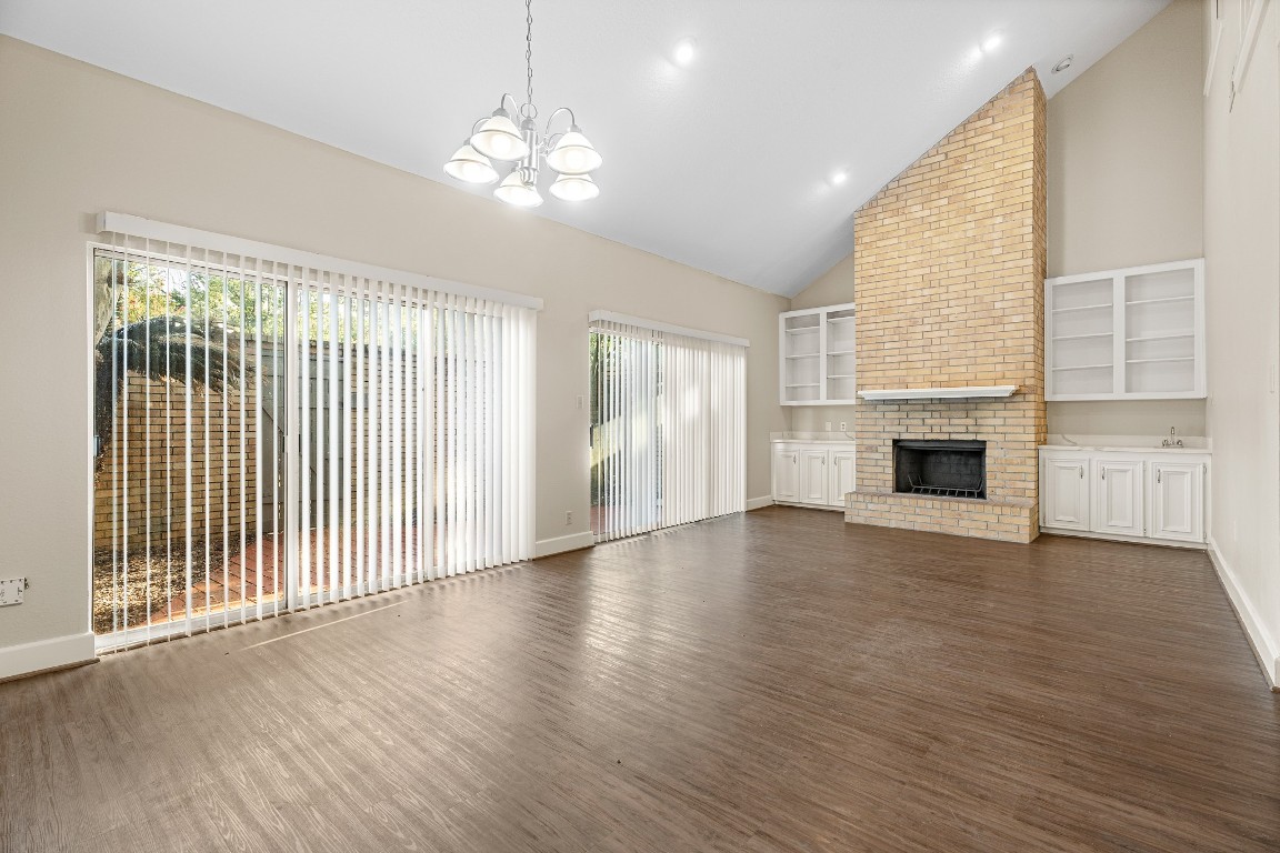 304 East Adoue Street Alvin, TX 77511 - Photo 4 of 12 an empty room with wooden floor fireplace and windows