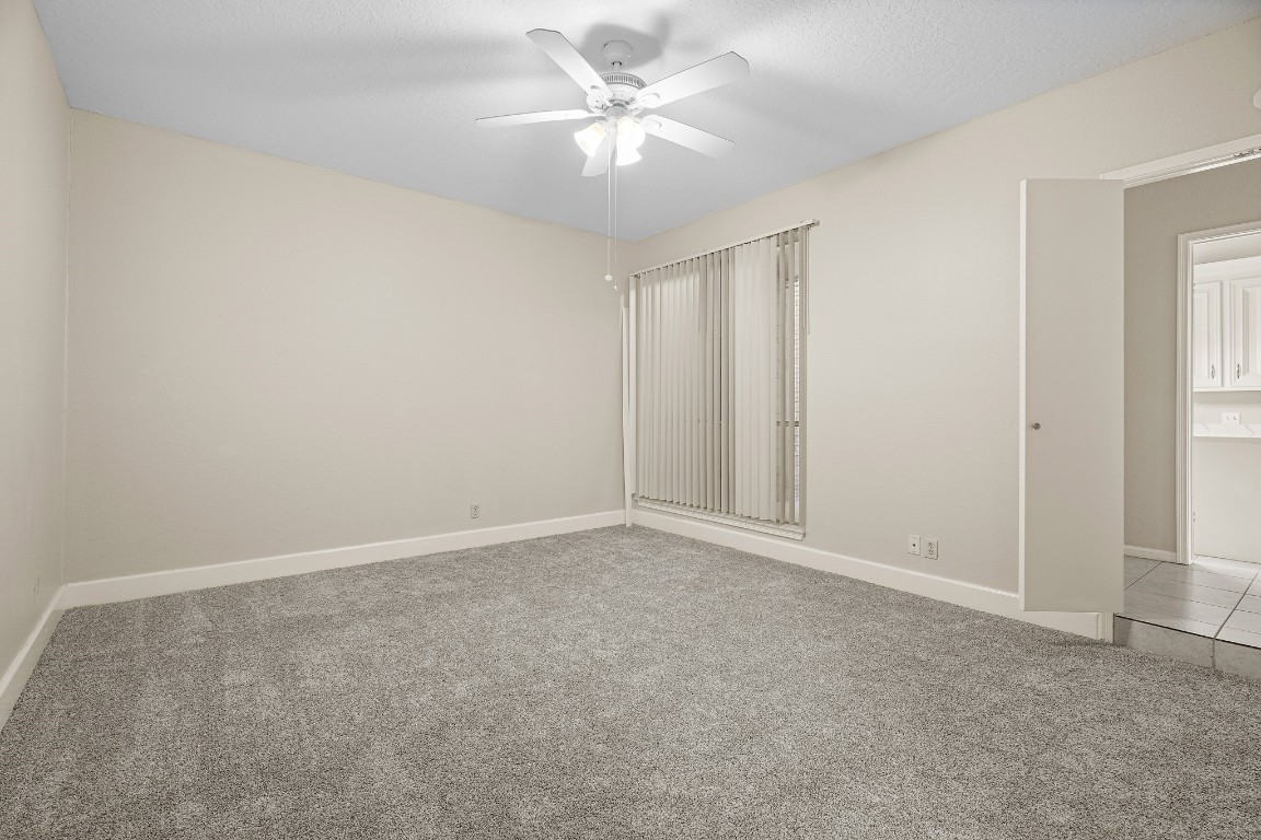 304 East Adoue Street Alvin, TX 77511 - Photo 5 of 12 an empty room with a chandelier fan and windows