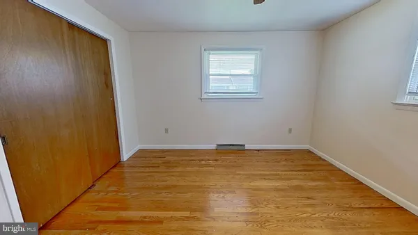 a view of an empty room with window and closet area