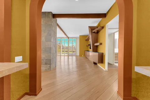 a view of an empty room with wooden floor and a fireplace