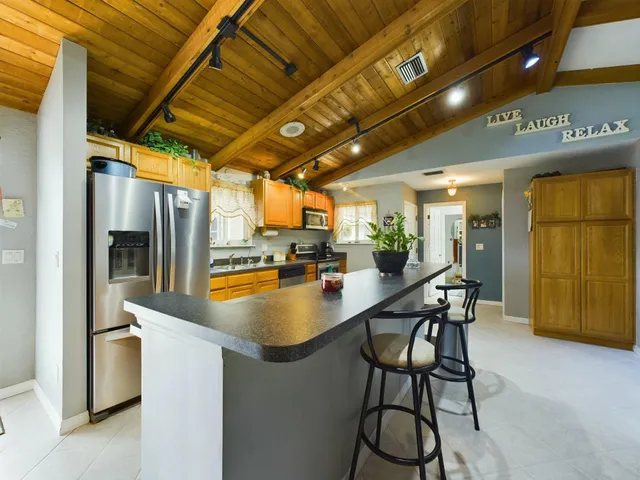 a kitchen with stainless steel appliances granite countertop a table chairs and a refrigerator