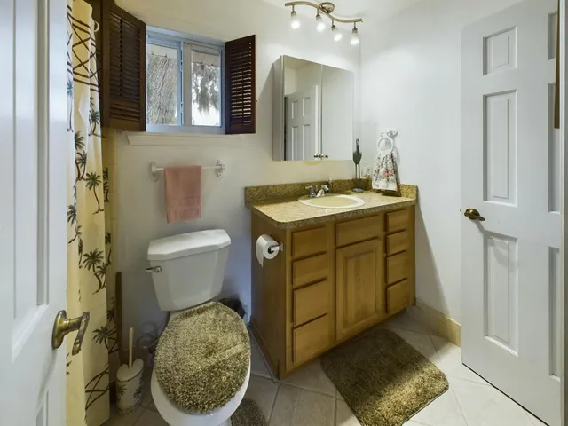 a bathroom with a granite countertop sink toilet and mirror