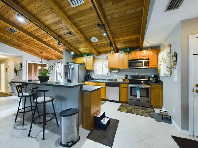 a kitchen with stainless steel appliances kitchen island granite countertop a table chairs and a wooden floor