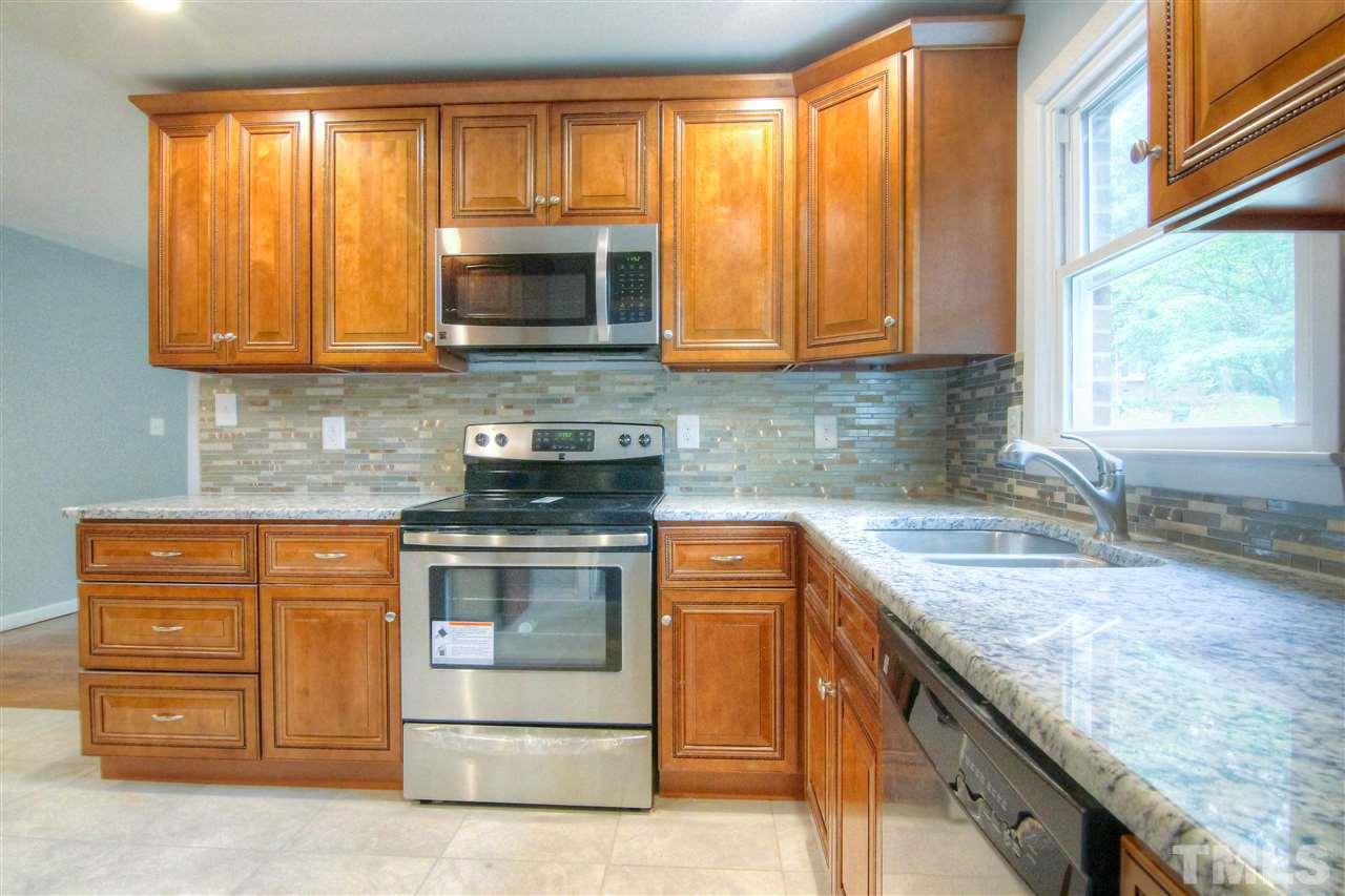 4608 Huntington Court Raleigh, NC 27609 - Photo 4 of 10 a kitchen with granite countertop wooden cabinets stainless steel appliances and a window