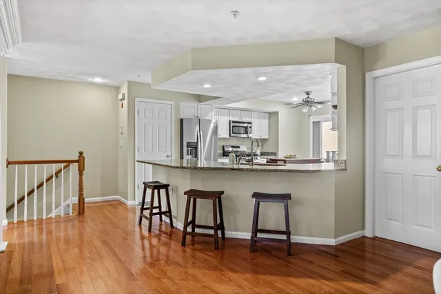 a kitchen with stainless steel appliances granite countertop a kitchen island hardwood floor and a sink