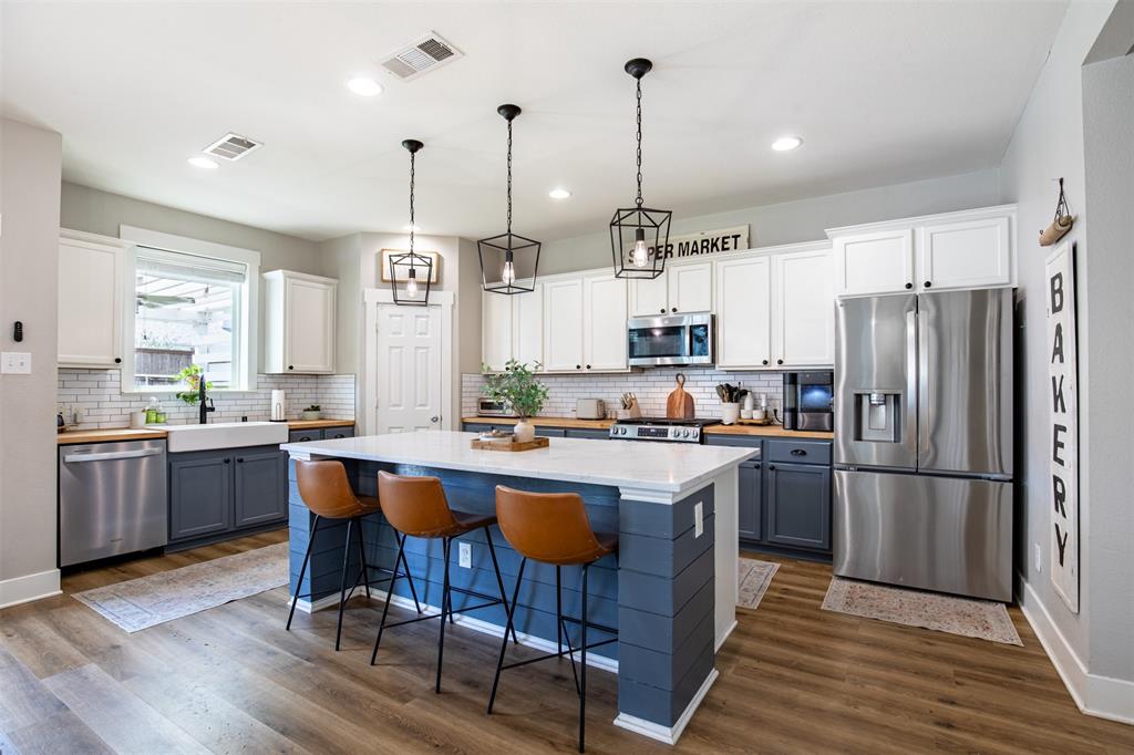 416 Allbright Road Celina, TX 75009 - Photo 11 of 40 a kitchen with stainless steel appliances granite countertop a refrigerator a sink dishwasher a stove kitchen island and chairs with wooden floor