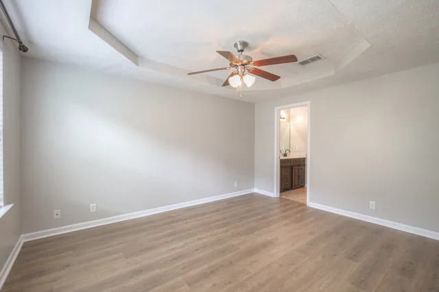 an empty room with wooden floor chandelier fan and closet area