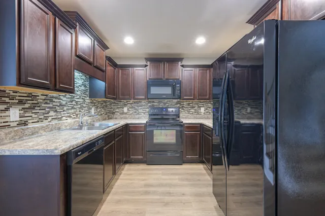 a kitchen with stainless steel appliances granite countertop wooden cabinets a sink and dishwasher