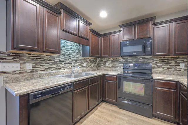 a kitchen with stainless steel appliances granite countertop wooden cabinets a sink and dishwasher