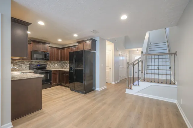 a kitchen with stainless steel appliances kitchen island granite countertop a refrigerator a sink a stove and oven