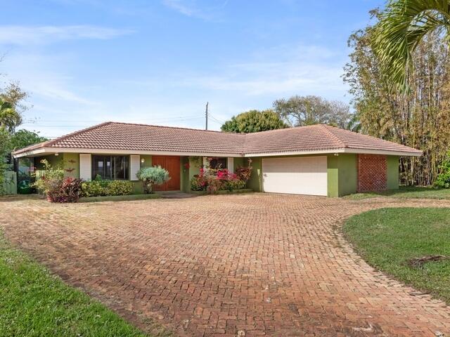1705 Ashby Road Juno Beach, FL 33408 - Photo 20 of 21 a front view of a house with a yard and garage