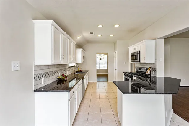 a kitchen with granite countertop a sink a stove top oven and refrigerator