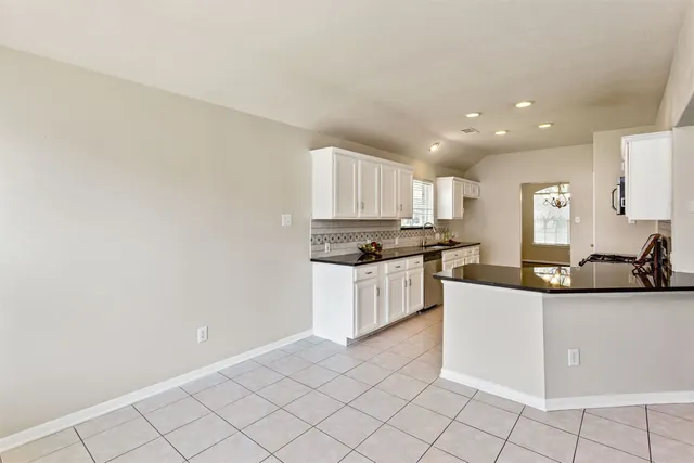 a kitchen with granite countertop white cabinets and white appliances