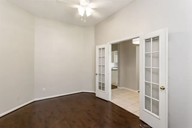 an empty room with wooden floor cabinet and windows