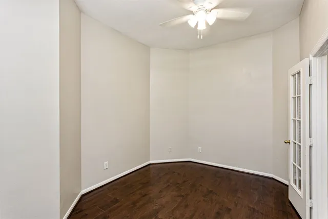 an empty room with wooden floor and fan