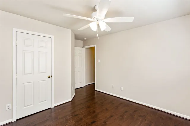 an empty room with wooden floor fan and windows