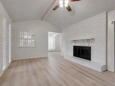 an empty room with windows and fireplace