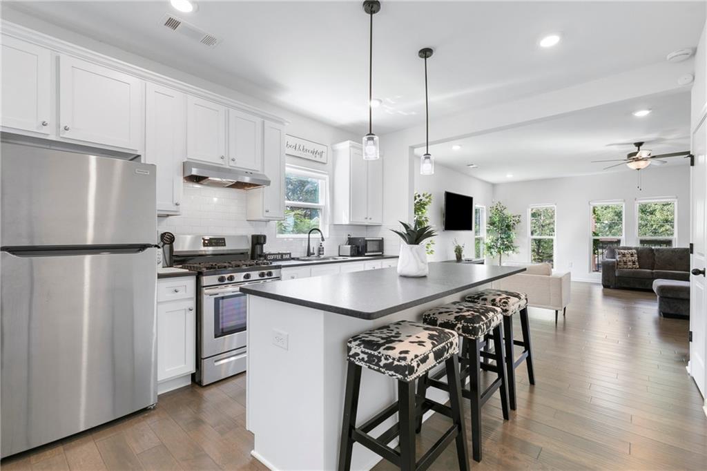 973 Mayson Turner Road Northwest Atlanta, GA 30314 - Photo 13 of 38 a kitchen with stainless steel appliances kitchen island granite countertop a sink a stove a refrigerator and island with wooden floor