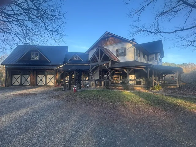 a view of a house with a yard plants and a large tree