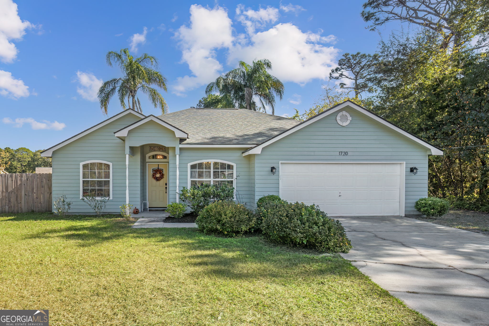 a front view of house with yard and trees in the background